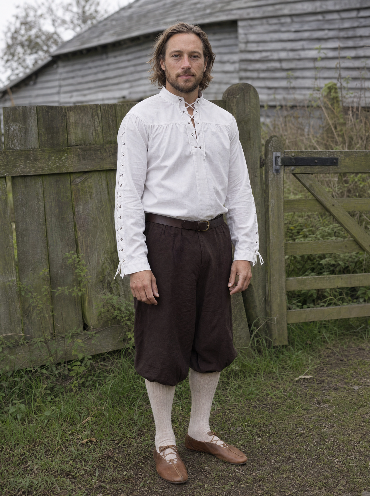 Man in a white Renaissance shirt with laced sleeves and dark trousers beside a wooden fence