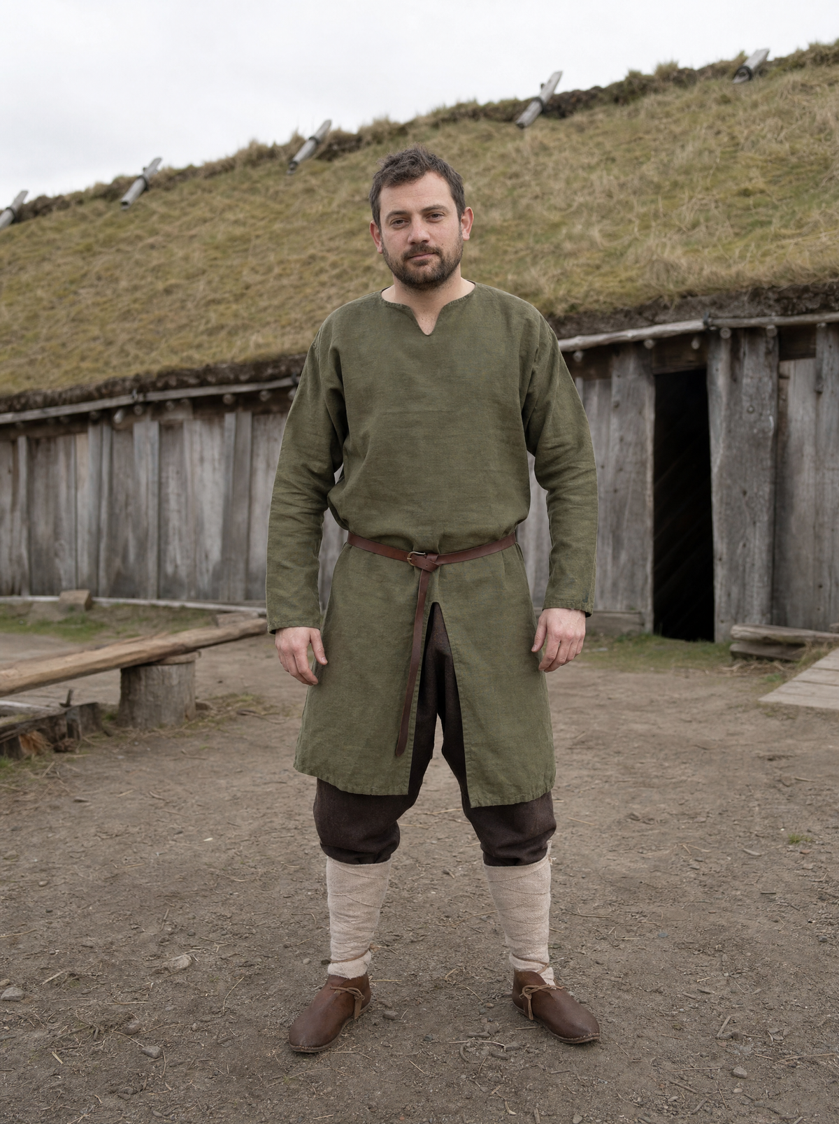 Man in a green cotton Viking tunic belted over dark trousers outdoors