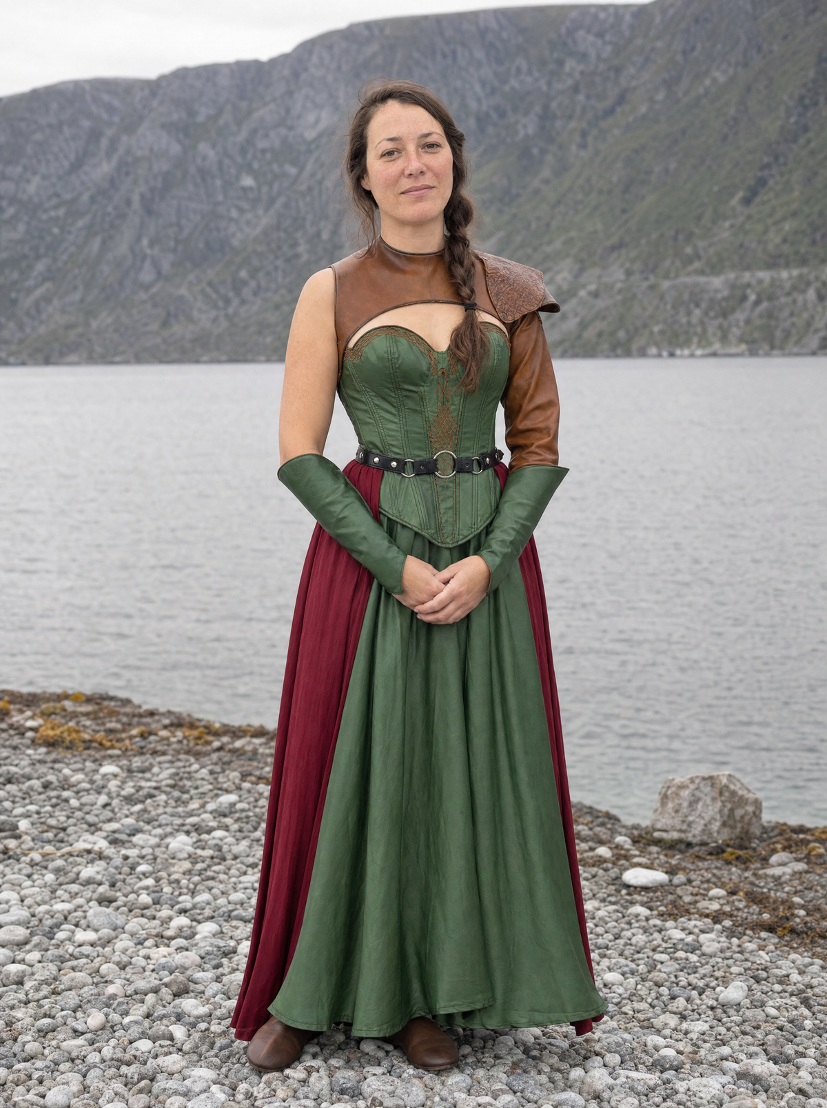 Woman in a green satin gown with a laced bodice and wine-red underskirt on a rocky shore