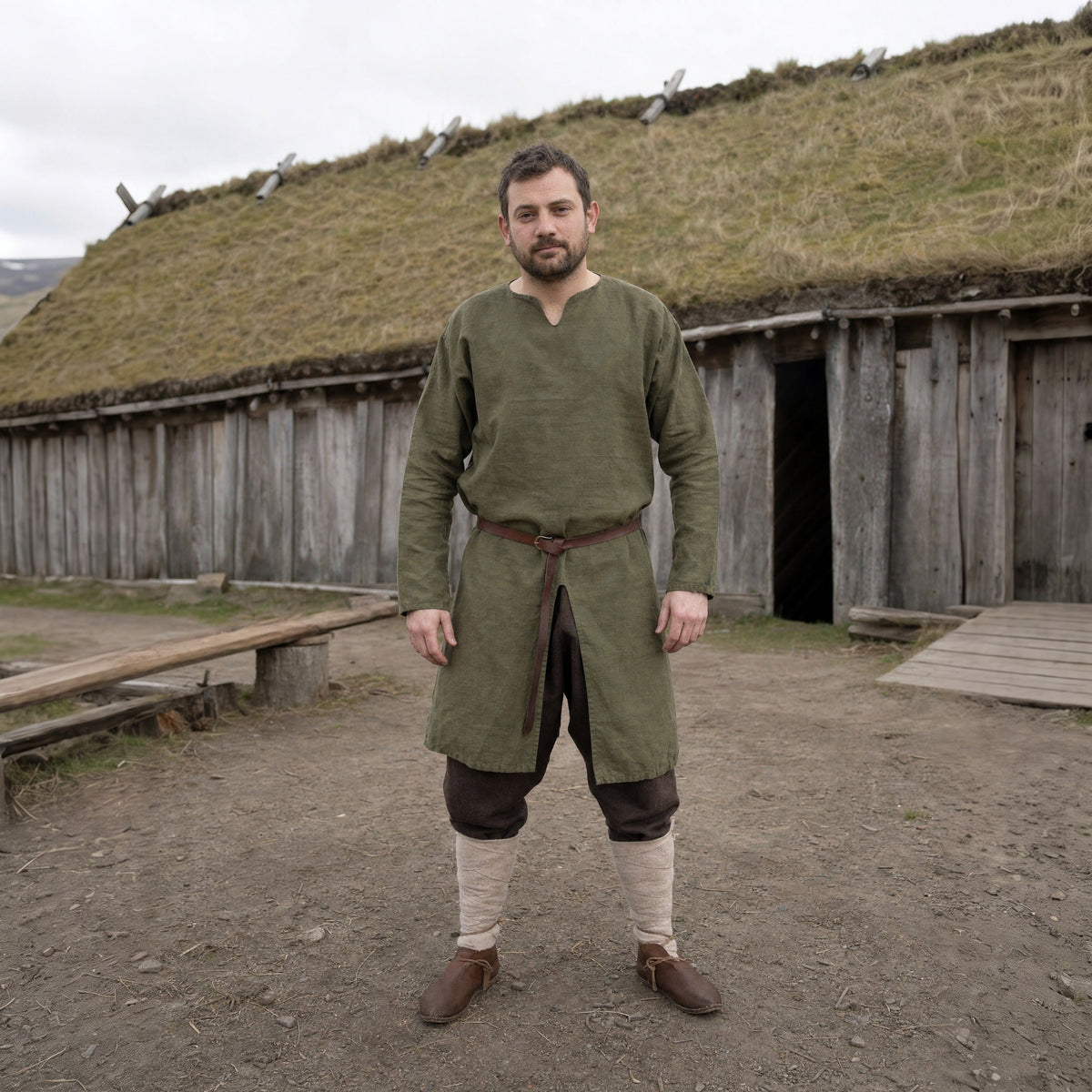 A man in the Viking Warrior look outdoors: green tunic, trousers, belt and boots