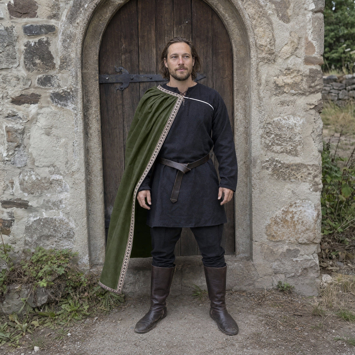 A man in the Dark Fantasy Warrior look outdoors: green velvet cape over a dark tunic