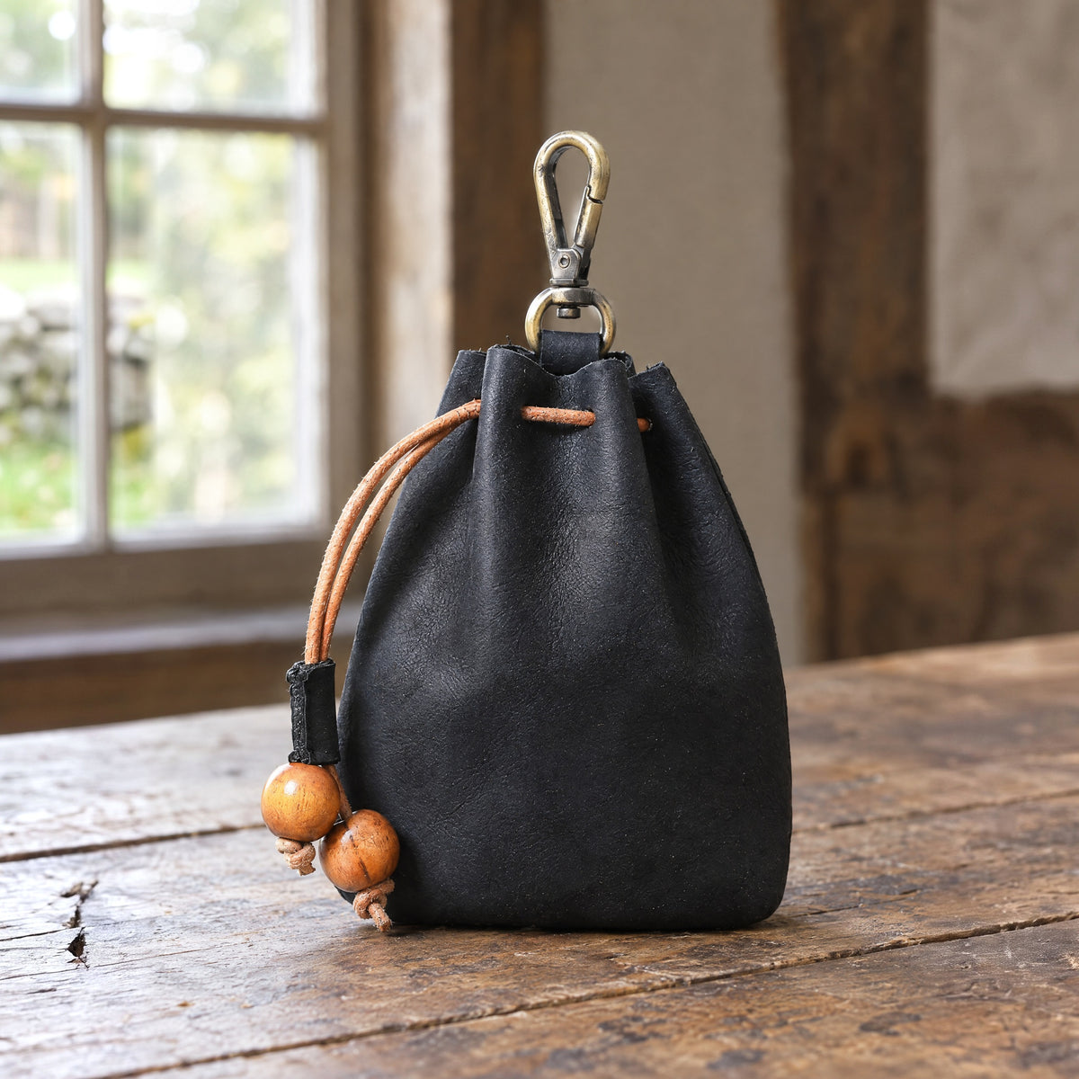 Black clip-on leather drawstring pouch on a rustic surface