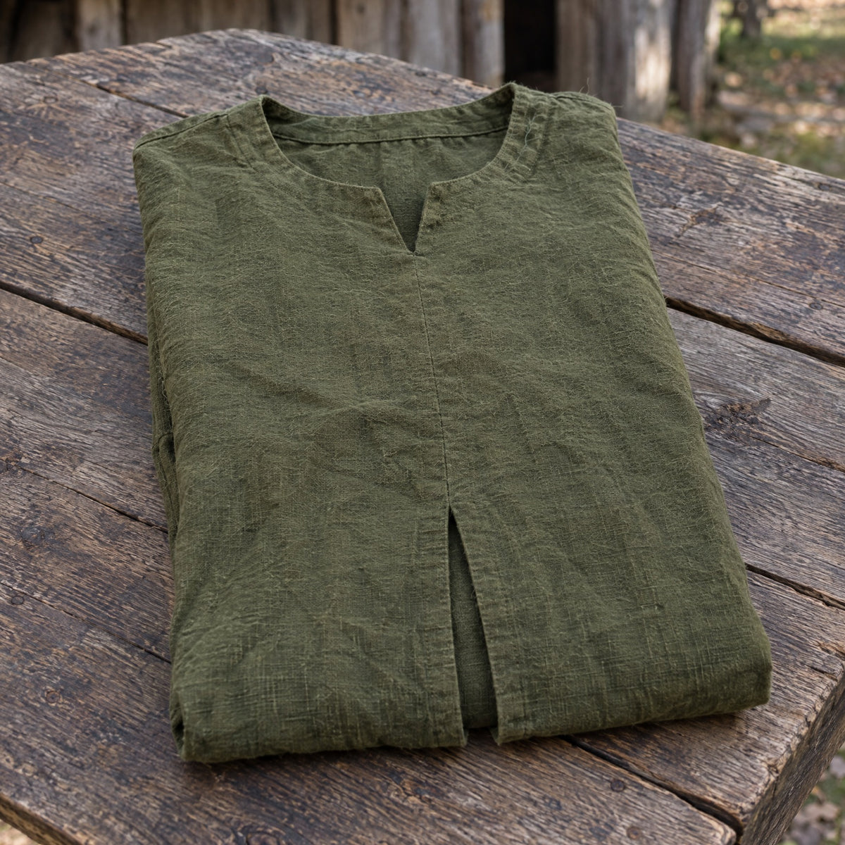 Green cotton viking tunic on a rustic surface