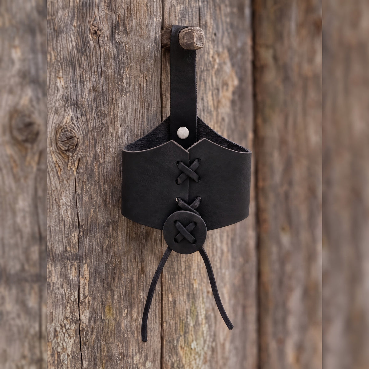 Black laced drinking horn holder on a rustic surface