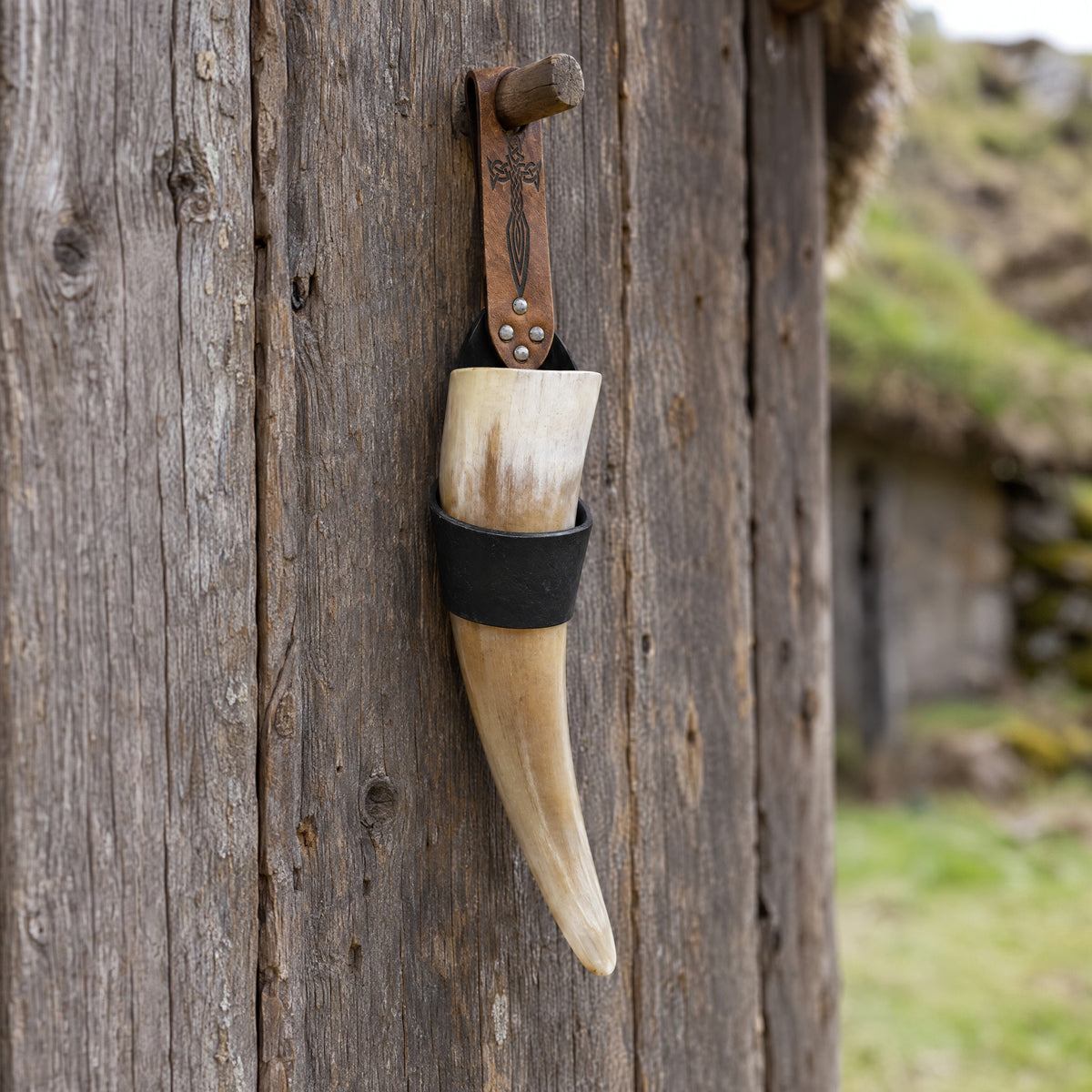Black drinking horn with embossed holder on a rustic surface