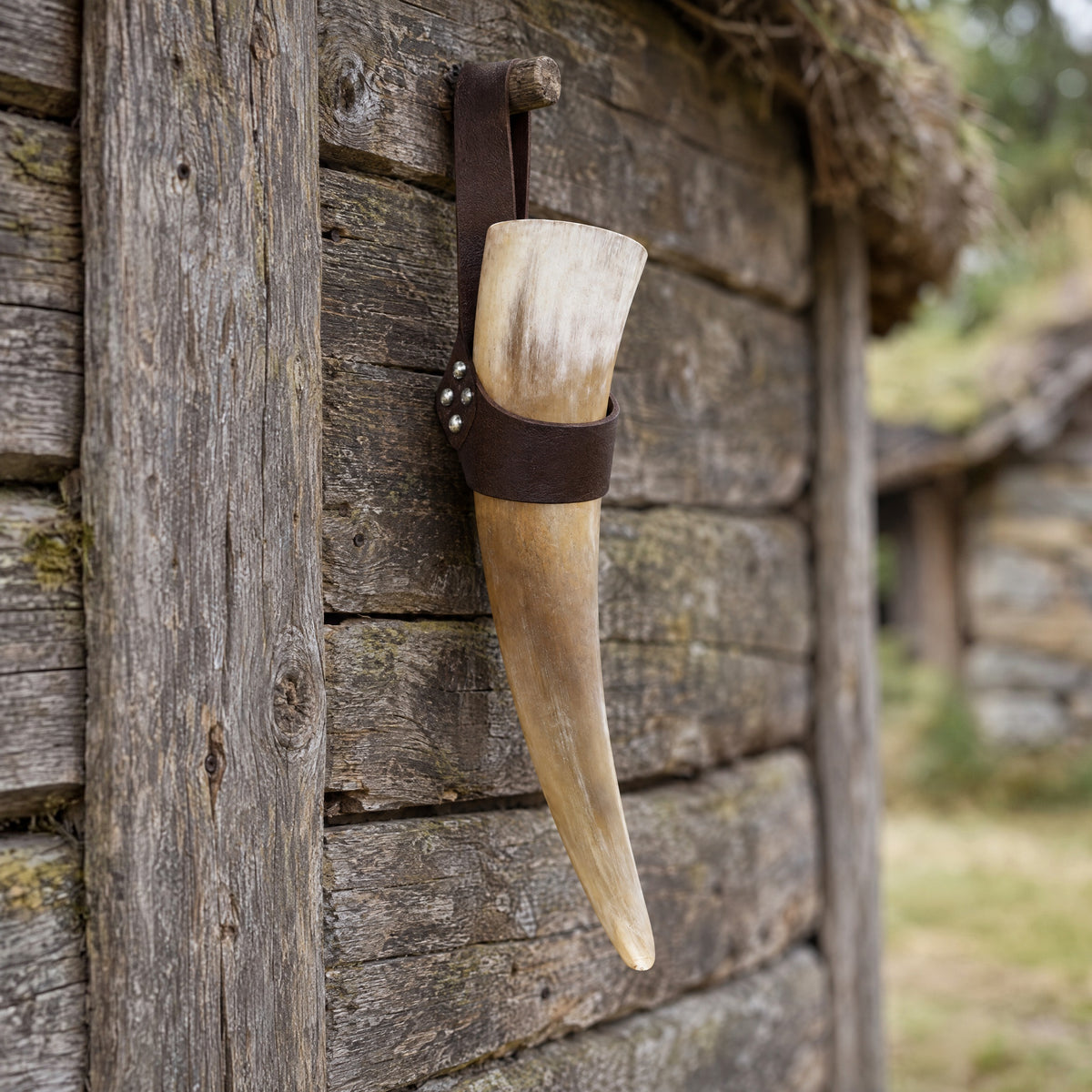 Brown drinking horn with riveted holder on a rustic surface