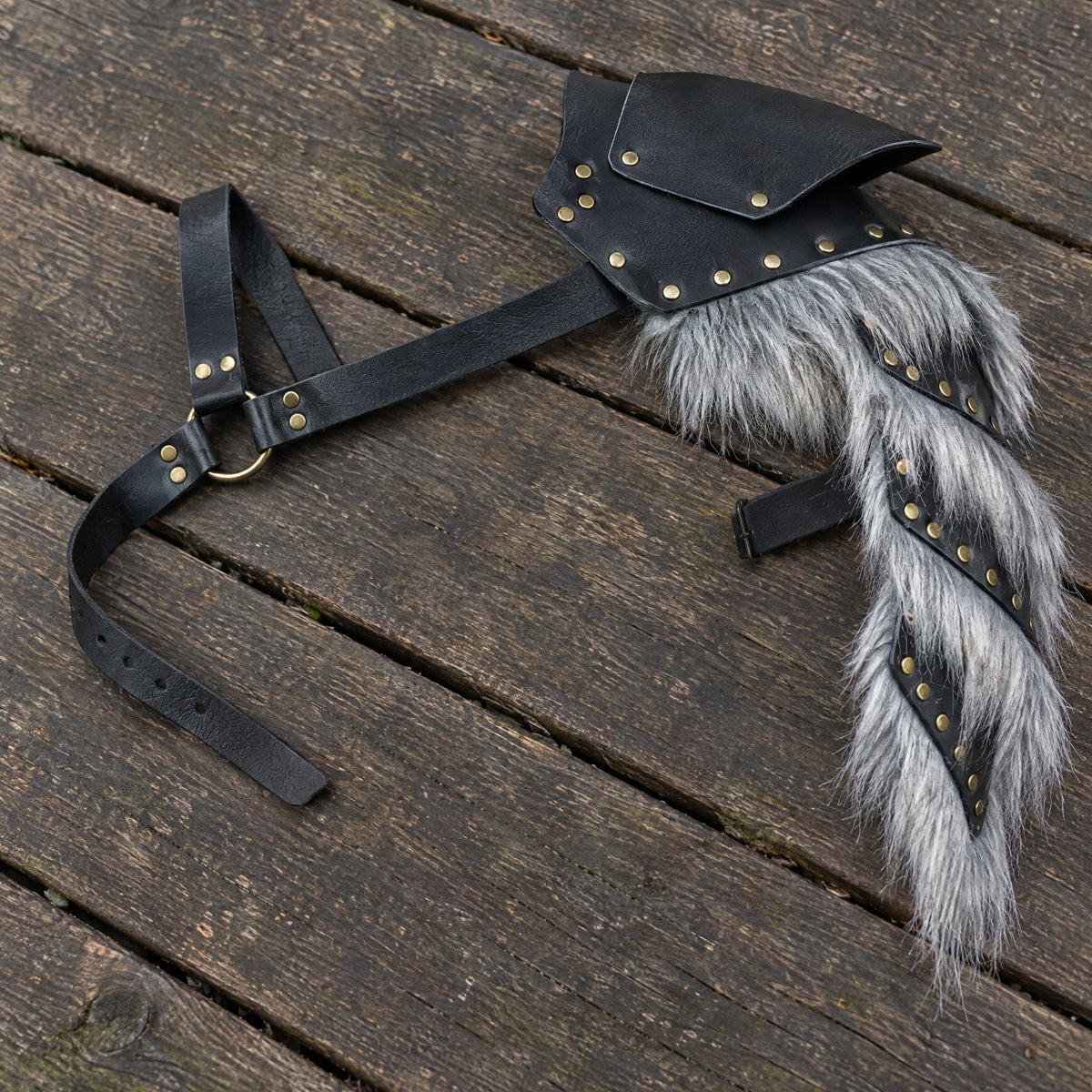 Black & grey buckled fur-trim pauldron on a rustic surface