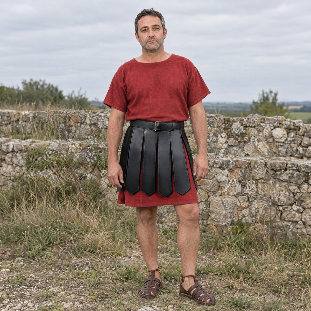 Black faux leather Roman strip skirt worn over a tunic outdoors, full-length front view