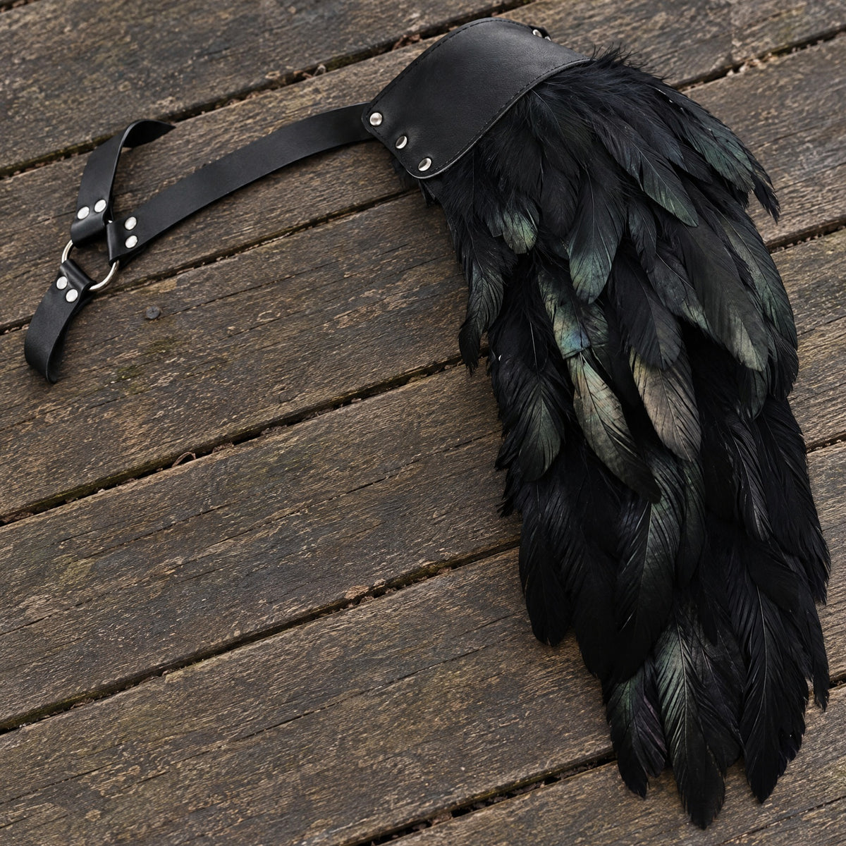 Black feathered single pauldron on a rustic surface