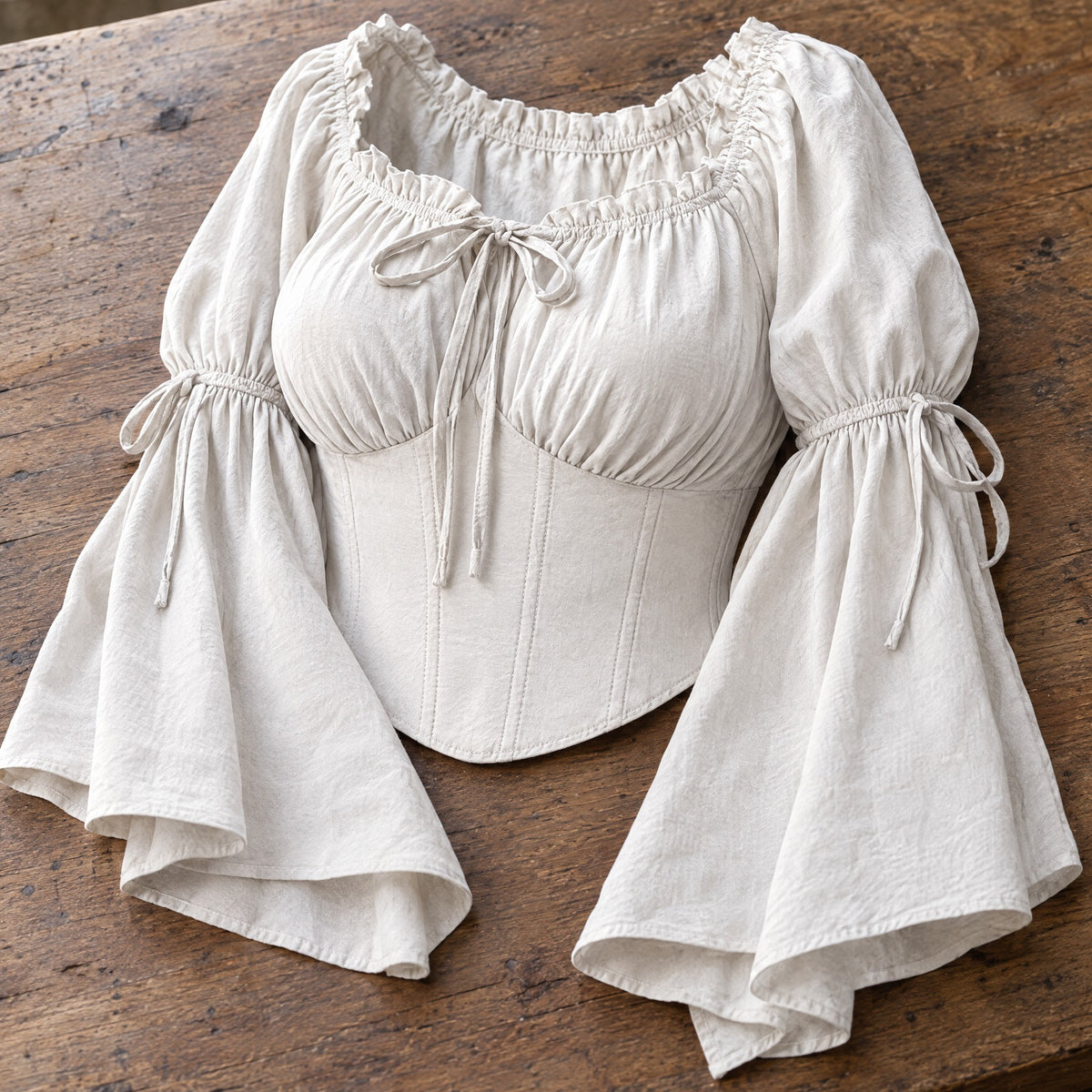White flared-sleeve renaissance blouse on a rustic surface