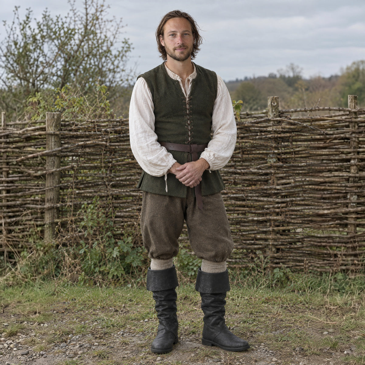 Black fold-over cuff renaissance boots worn by a man outdoors, full-length front view