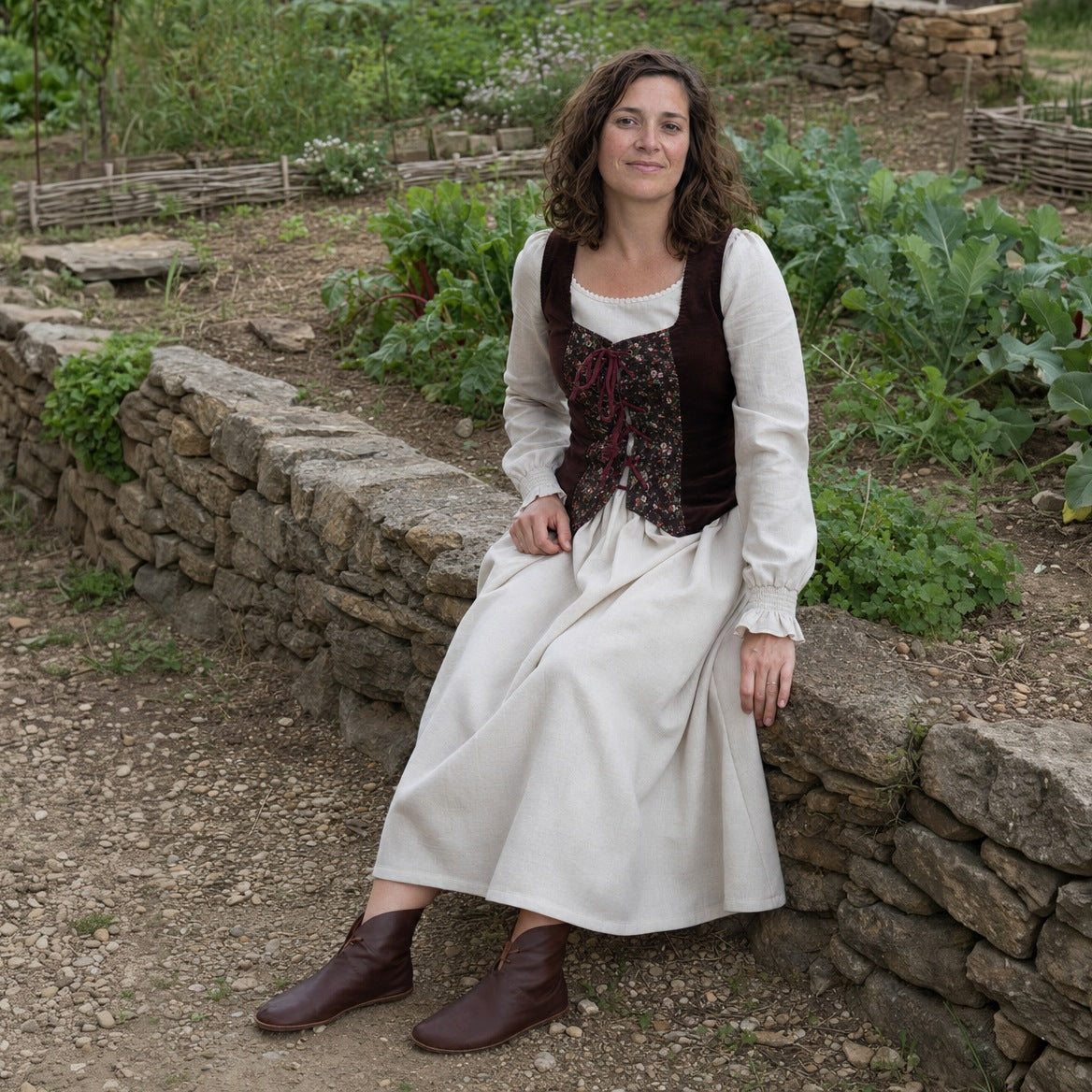 Full-skirt dress and laced vest set worn seated in a cottage garden