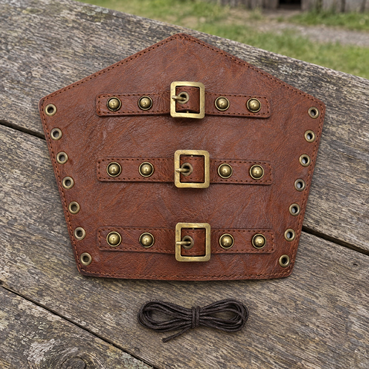 Brown gold-stud pentagon bracer on a rustic surface