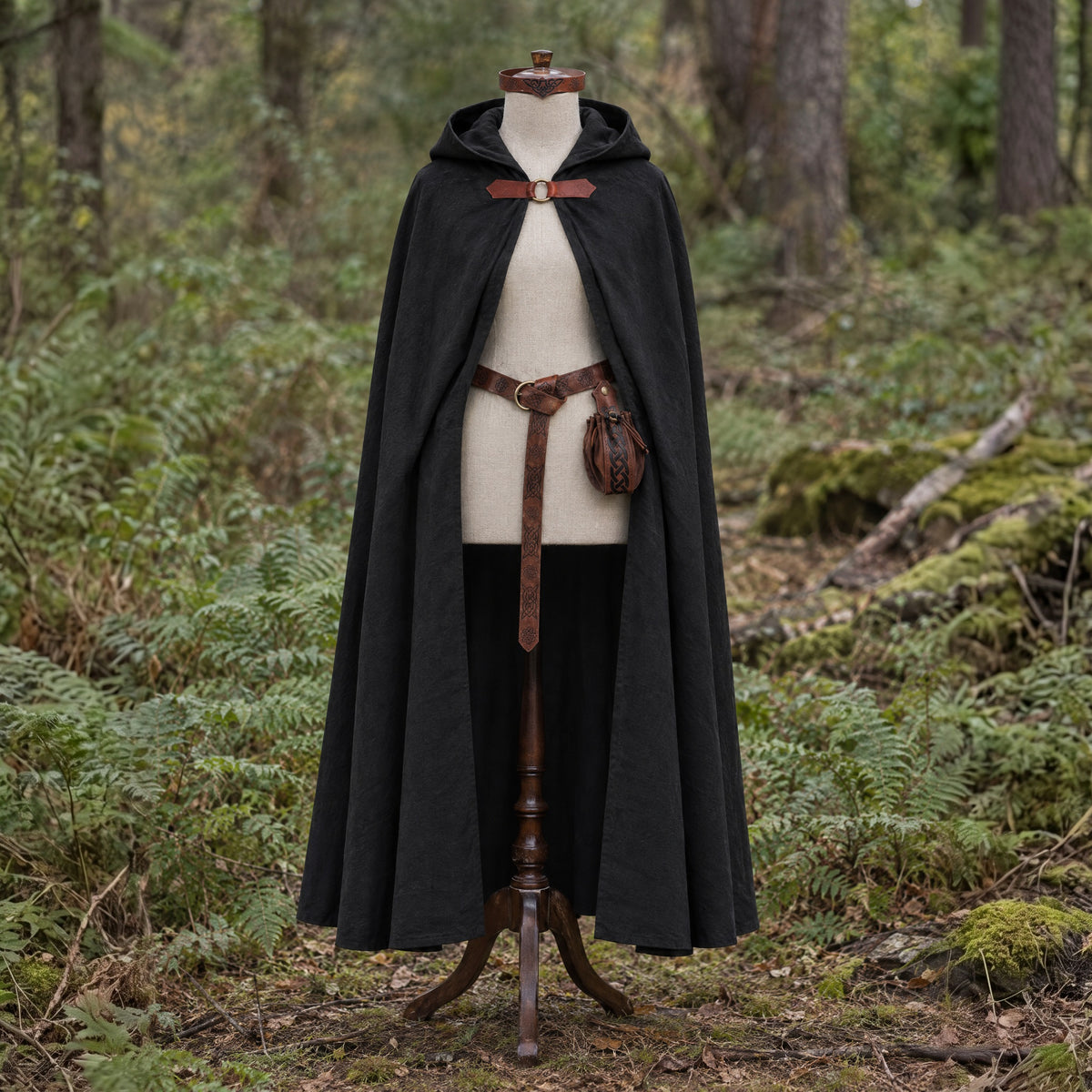 Black hooded cloak with belt and pouch on a dress form outdoors