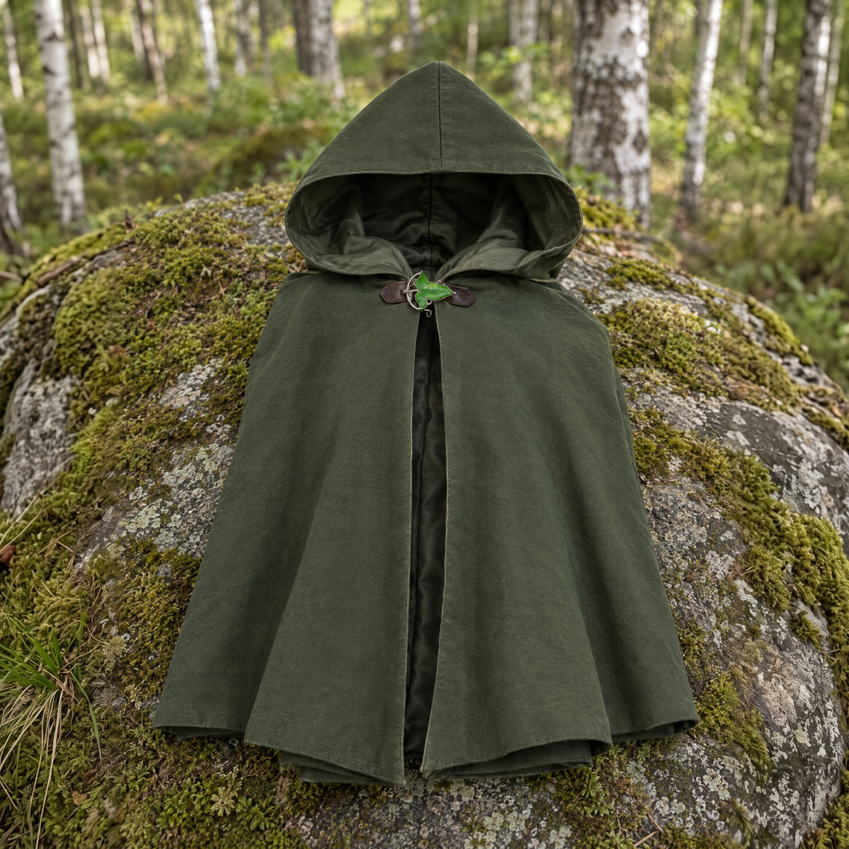 Green hooded cloak with leaf brooch on a rustic surface