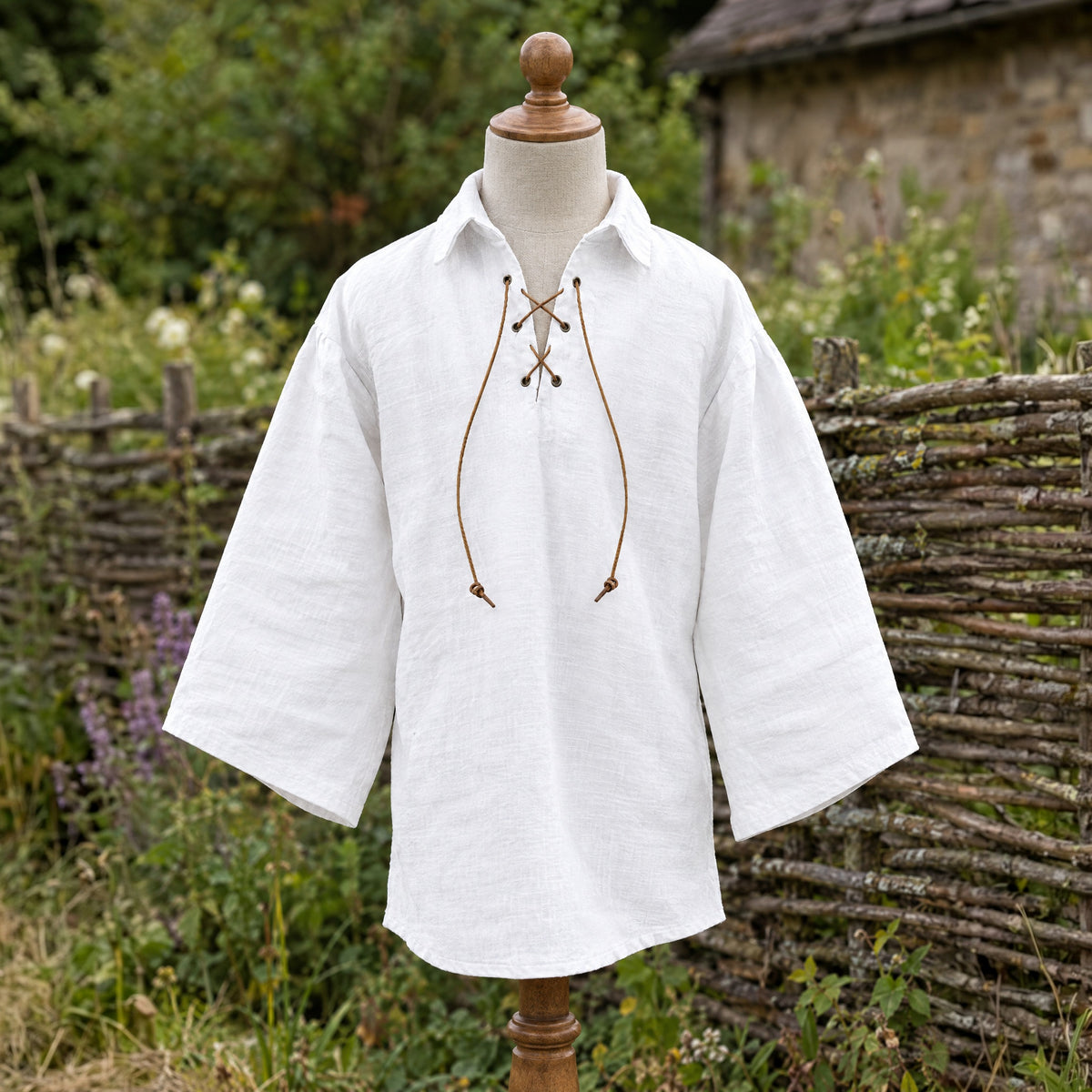 White kids' lace-up renaissance shirt on a dress form outdoors