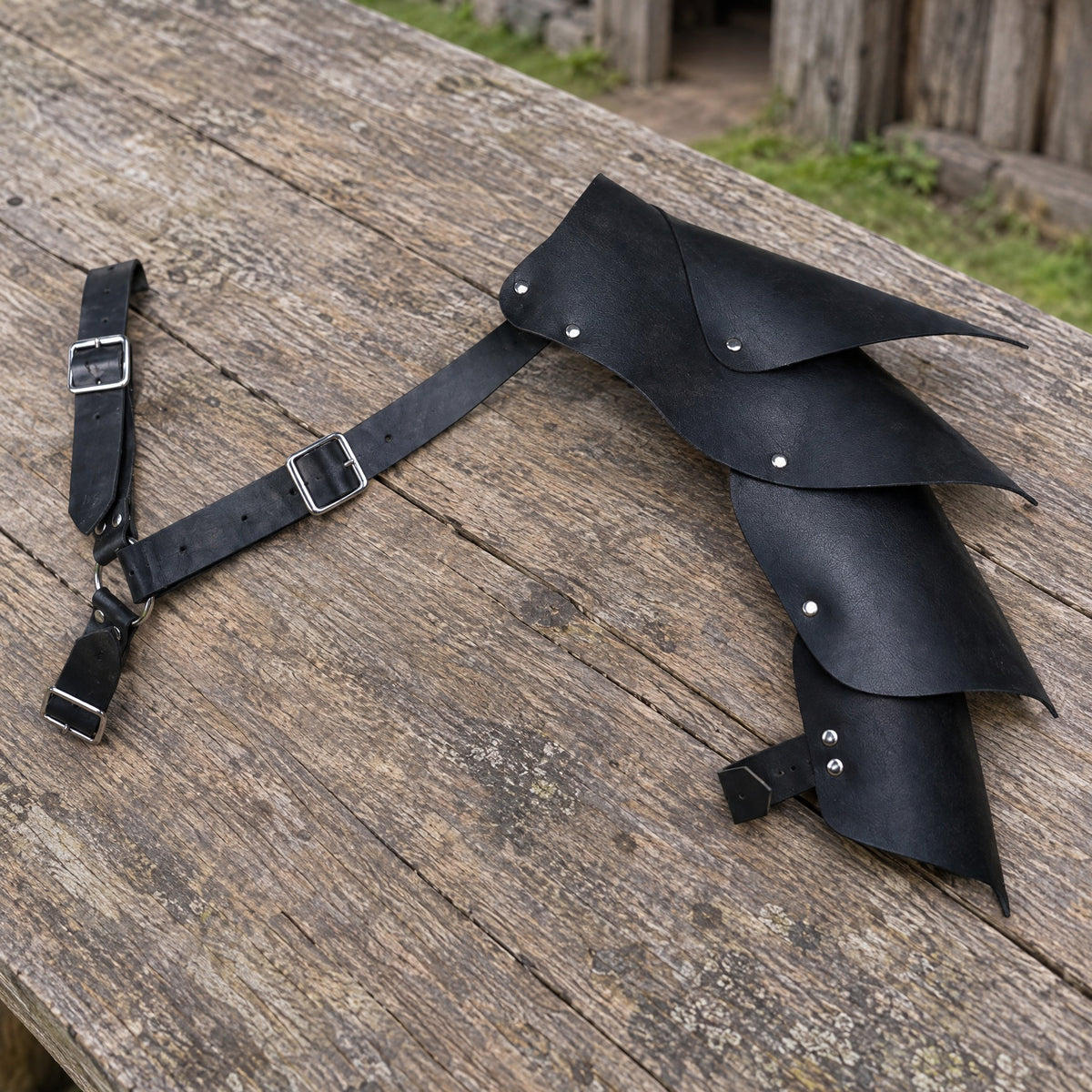 Black layered shoulder armour on a rustic surface