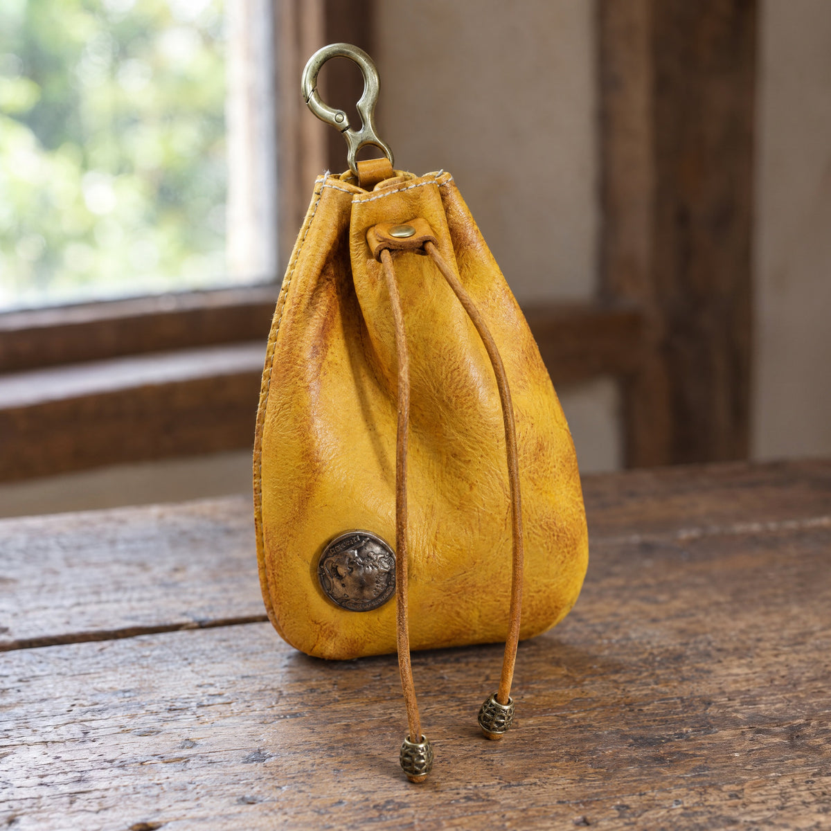 Yellow leather drawstring coin pouch on a rustic surface