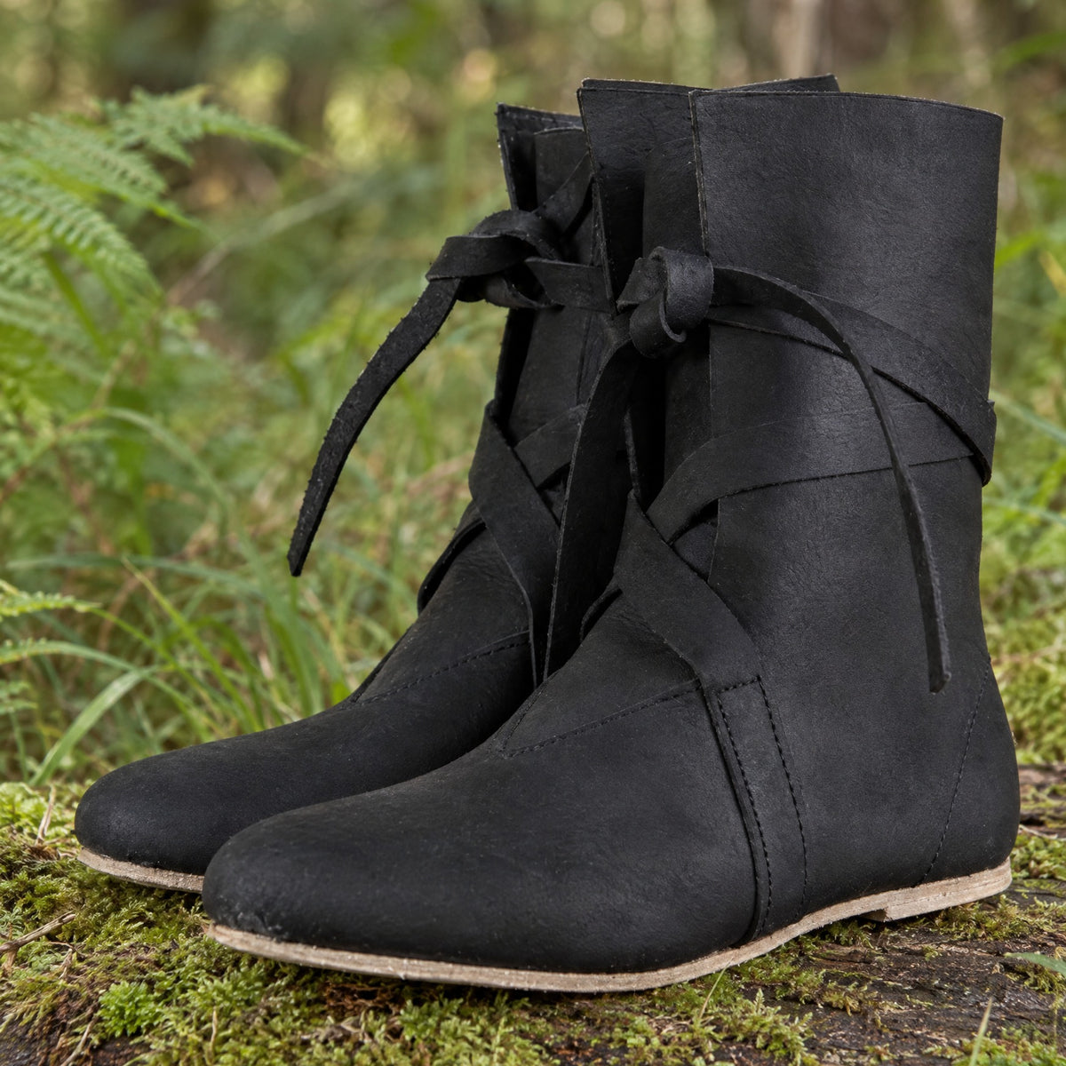 Black low faux leather boots on a rustic surface