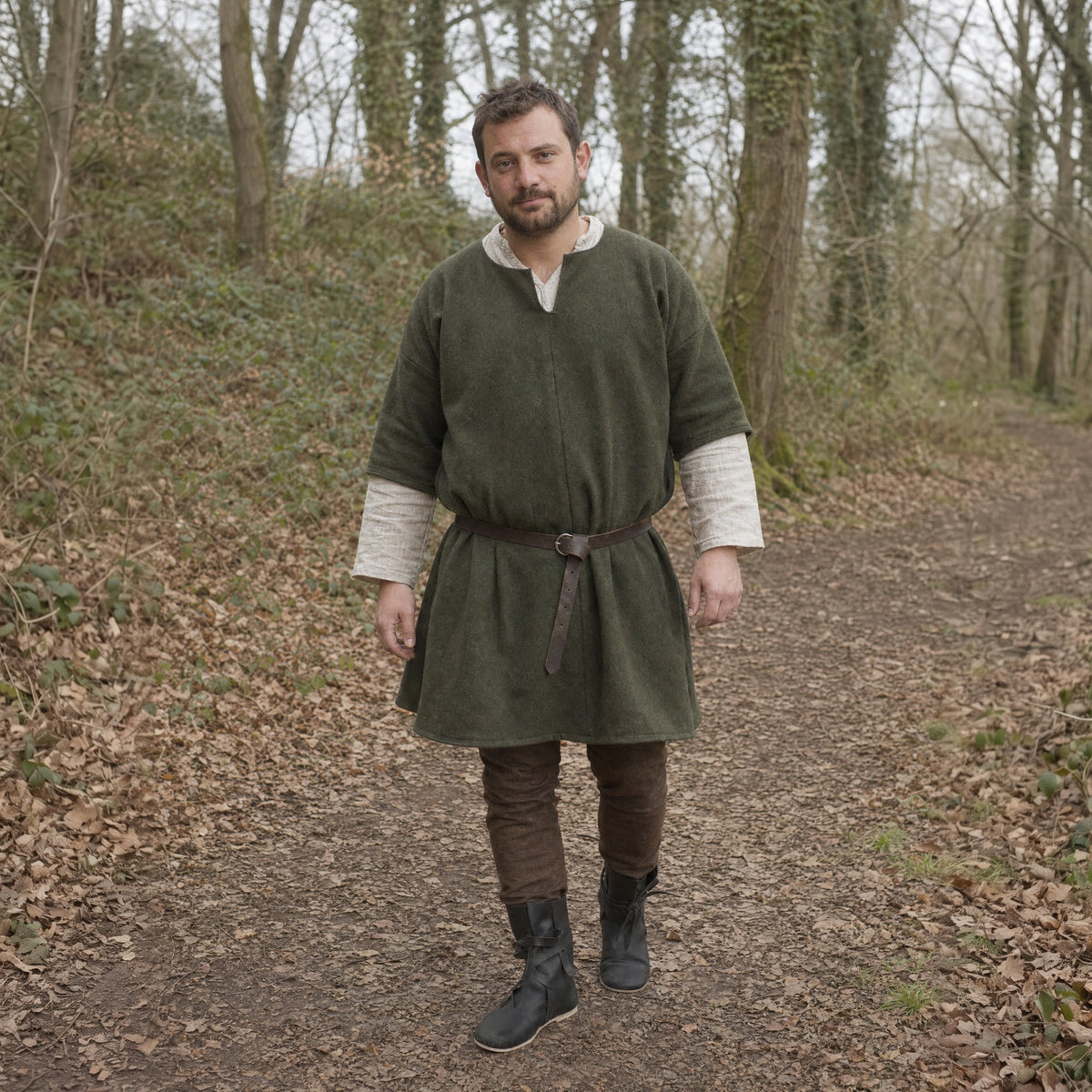 Black low faux leather boots worn by a man outdoors, full-length front view