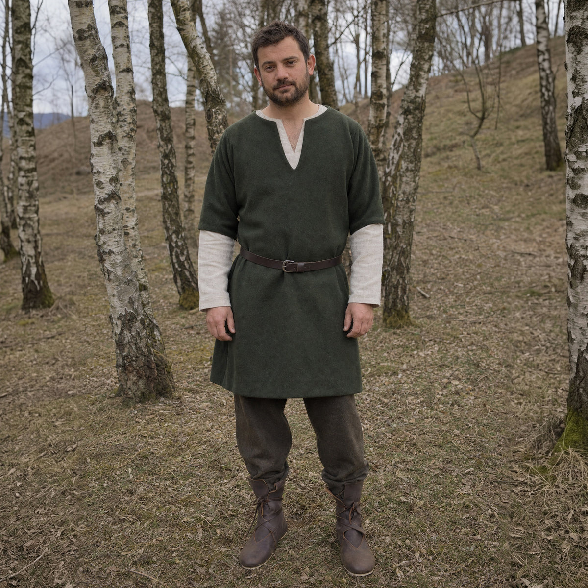 Brown low faux leather boots worn by a man outdoors, full-length front view