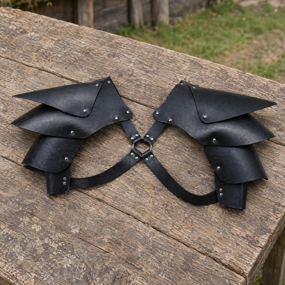 Black pointed double shoulder armour on a rustic surface