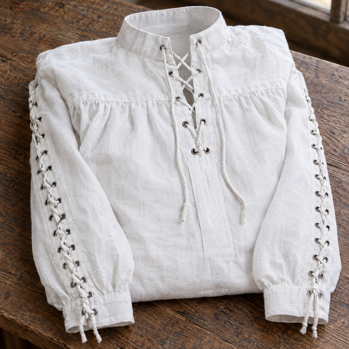 White renaissance shirt with laced sleeves on a rustic surface