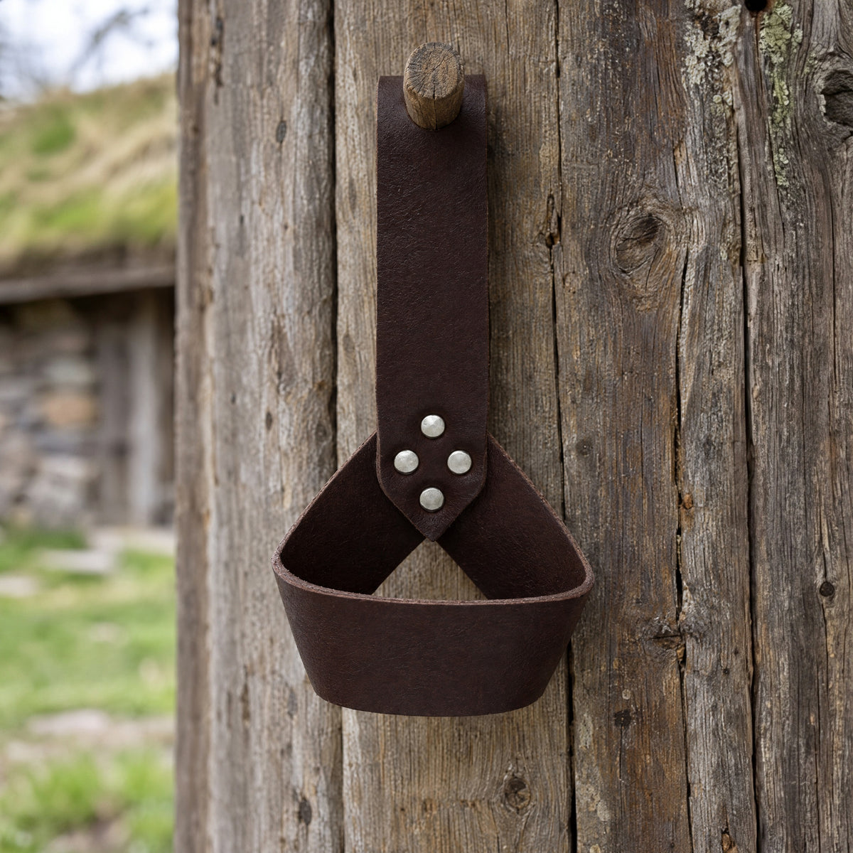 Brown riveted belt frog for horn or sword on a rustic surface
