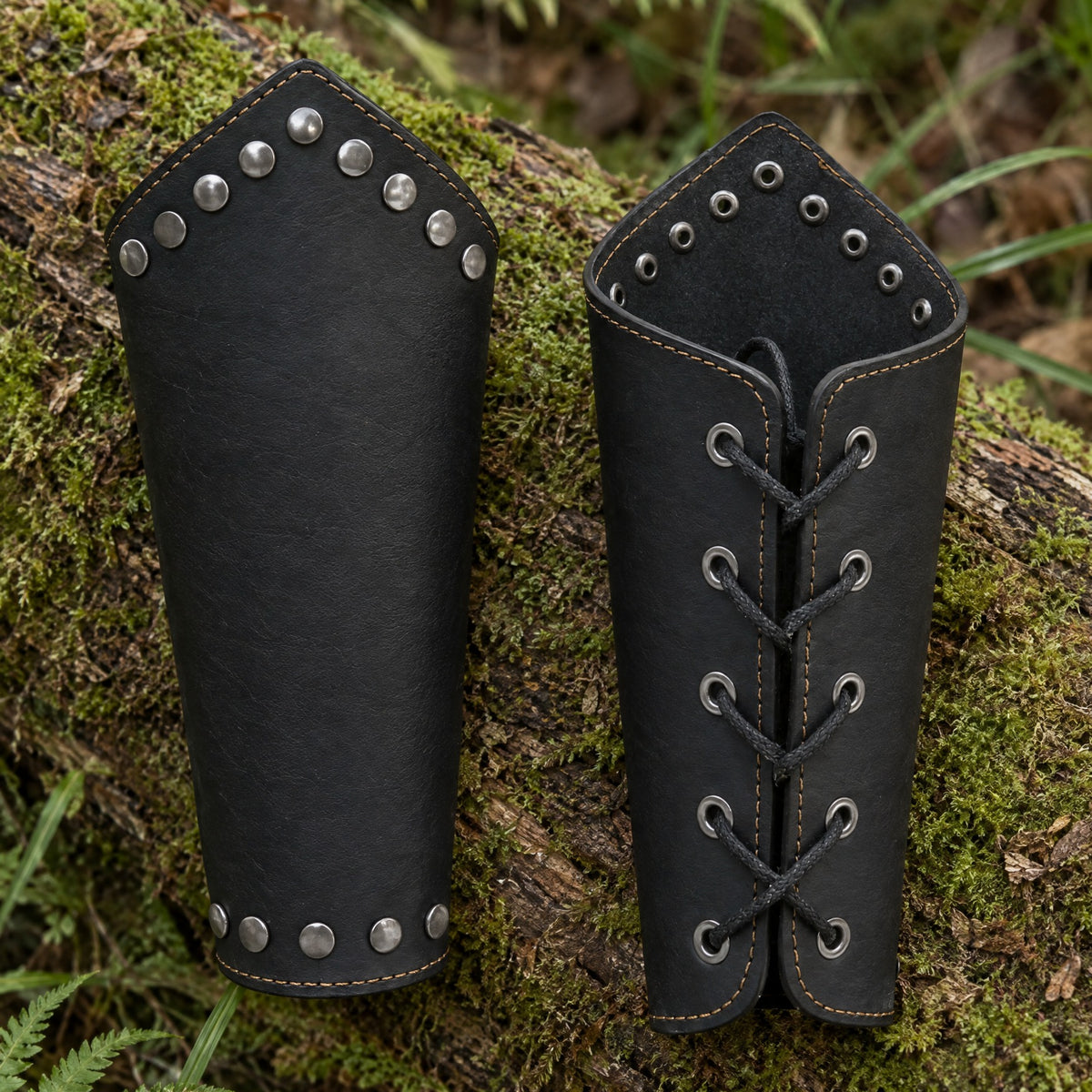 Black riveted studded-edge bracers on a rustic surface
