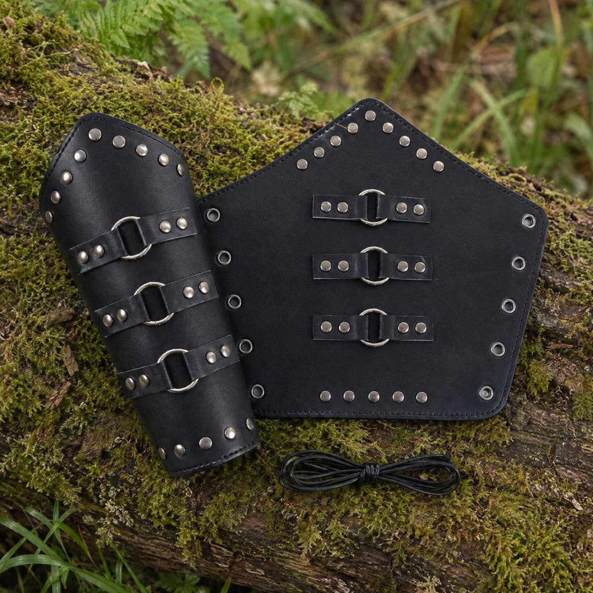 Black riveted three-ring bracers on a rustic surface