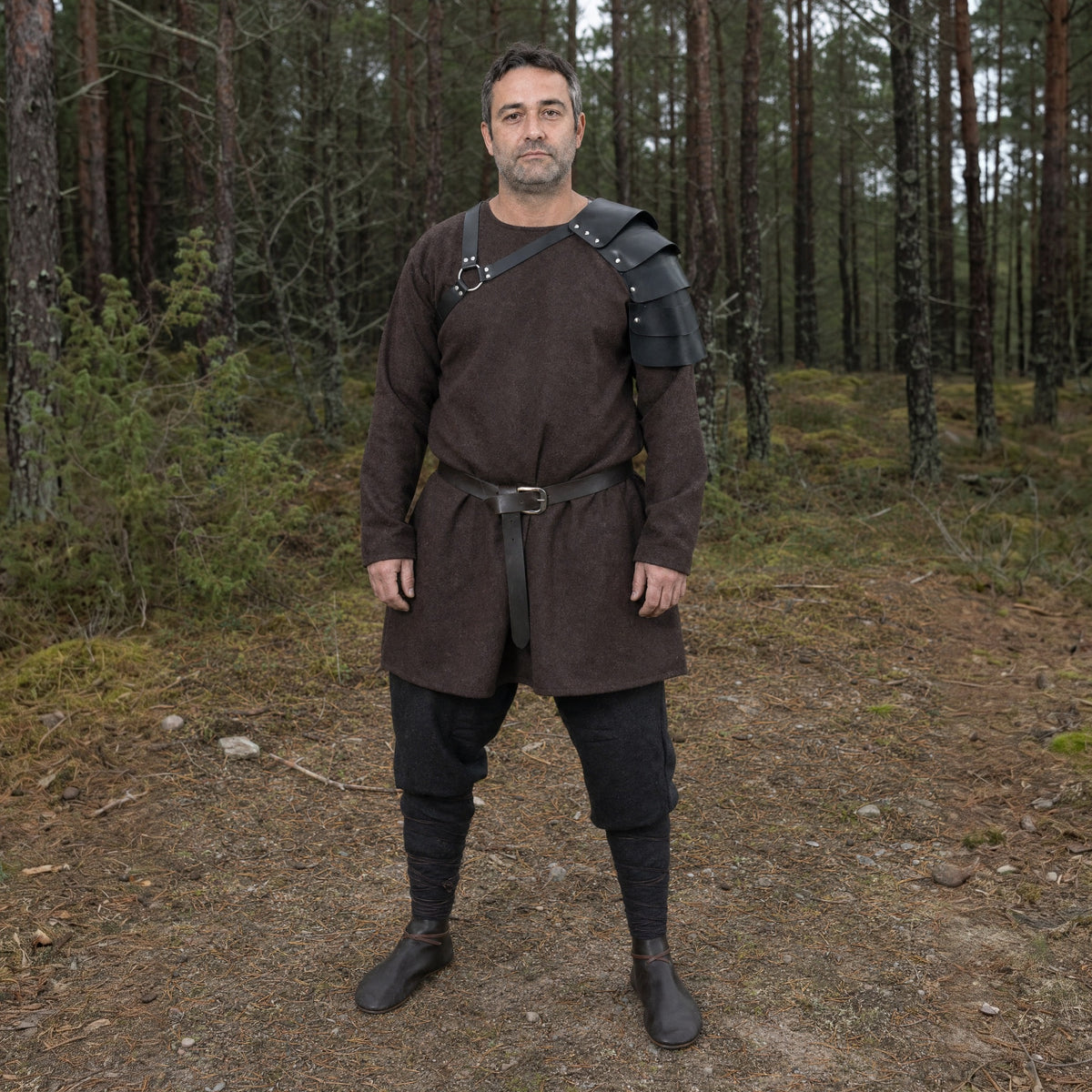 Black segmented single pauldron worn outdoors, full-length front view