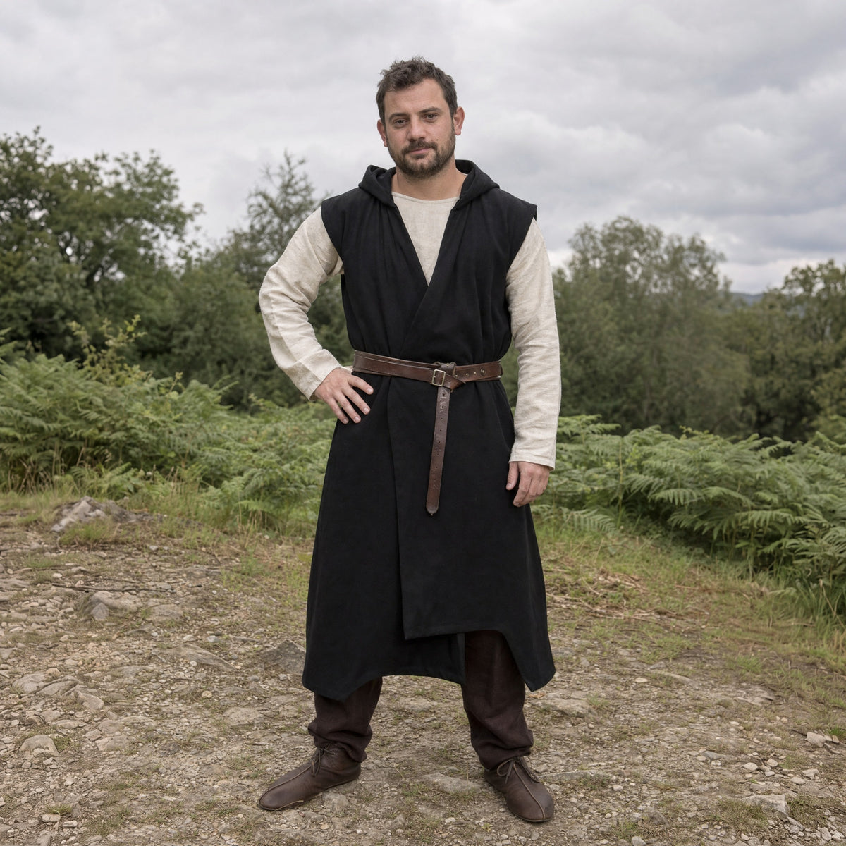 Black sleeveless cotton tunic worn by a man outdoors, full-length front view
