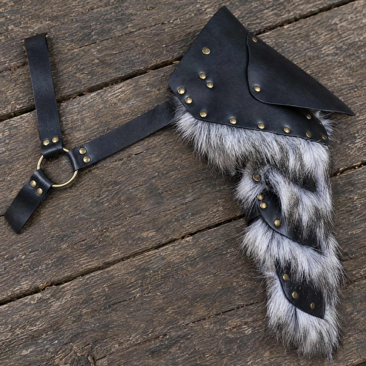 Black studded single pauldron on a rustic surface