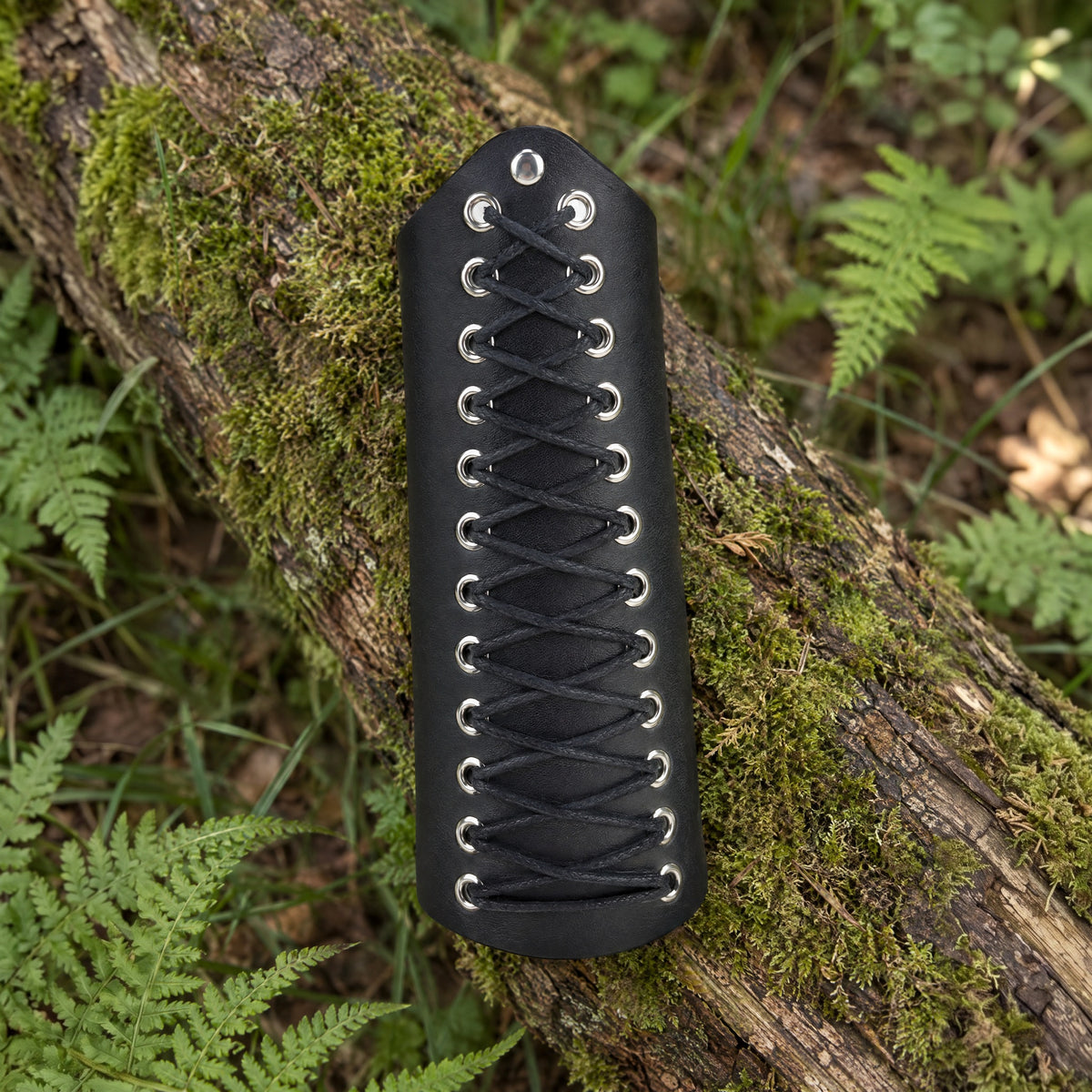Black tapered laced bracer on a rustic surface