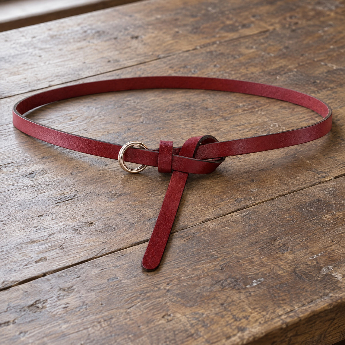 Red thin leather ring belt on a rustic surface