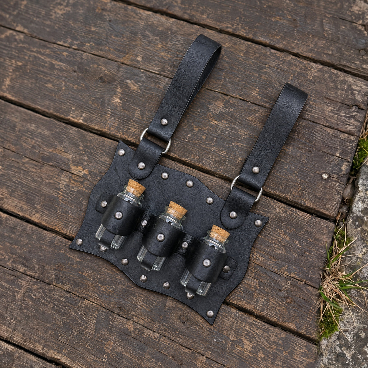 Black three-vial potion belt holder on a rustic surface
