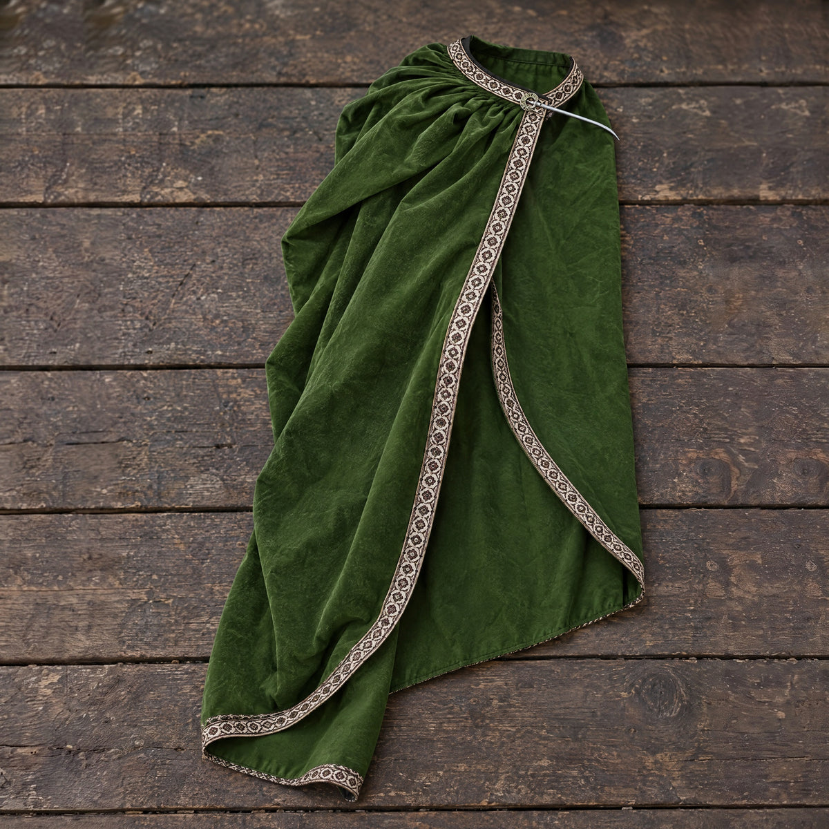 Green velvet one-shoulder cape on a rustic surface