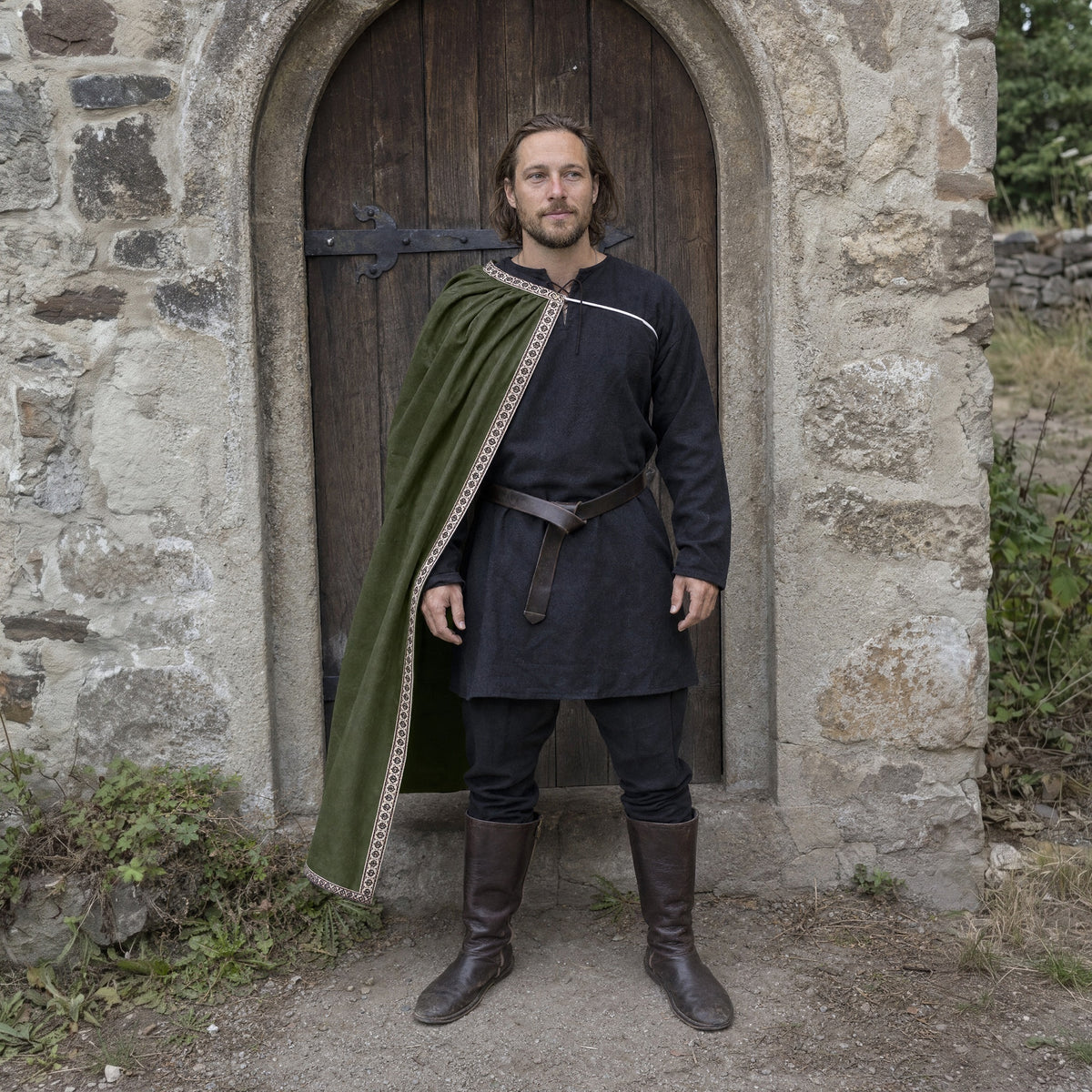 Green velvet one-shoulder cape worn by a man outdoors, full-length front view